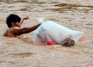 Para levar os filhos à escola, pais fazem a travessia do rio com as crianças dentro de sacos plásticos