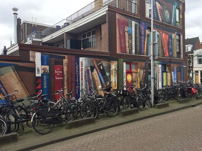 sensivel-mente.com - Artistas holandeses pintam estante gigante em um prédio de apartamentos com os livros favoritos dos moradores