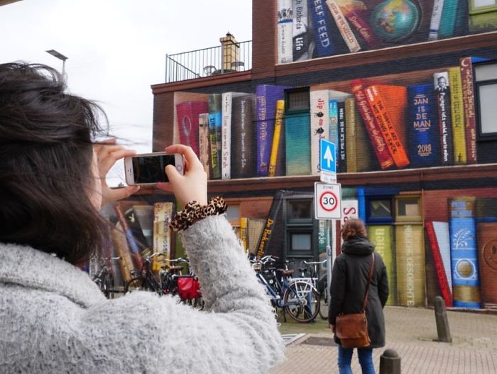 sensivel-mente.com - Artistas holandeses pintam estante gigante em um prédio de apartamentos com os livros favoritos dos moradores