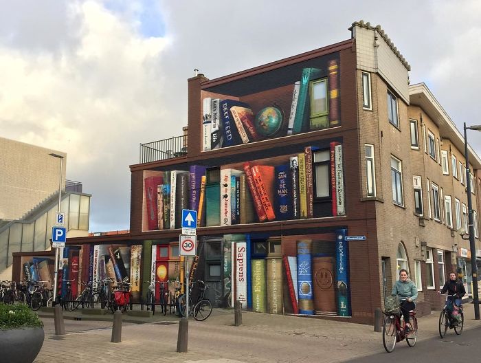 sensivel-mente.com - Artistas holandeses pintam estante gigante em um prédio de apartamentos com os livros favoritos dos moradores