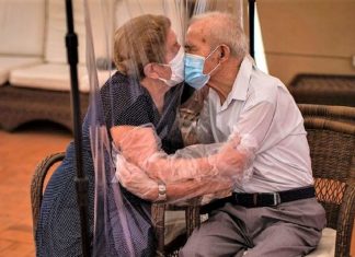 Casal de idosos se beijam na pandemia através de uma cortina plástica, provando que não há barreiras para o amor